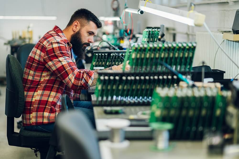 Produktionsmitarbeiter in der Elektronikfertigung lötet Platinen